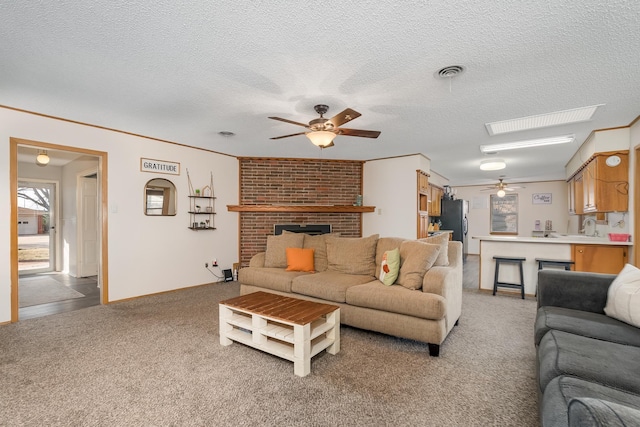 living room featuring ceiling fan, a textured ceiling, light colored carpet, a fireplace, and visible vents