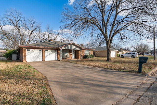 view of front of property featuring an attached garage, brick siding, driveway, a chimney, and a front yard