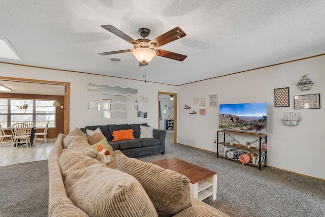 living room featuring ceiling fan, a textured ceiling, carpet flooring, and crown molding