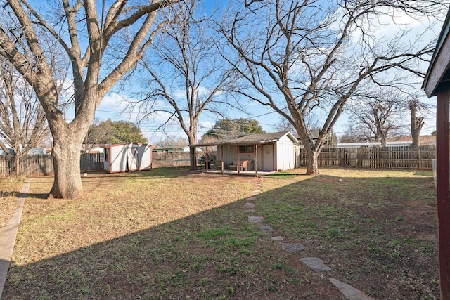 view of yard with a storage shed, a fenced backyard, and an outbuilding