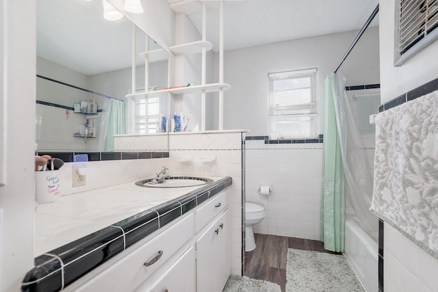 full bath featuring toilet, plenty of natural light, tile walls, and wood finished floors