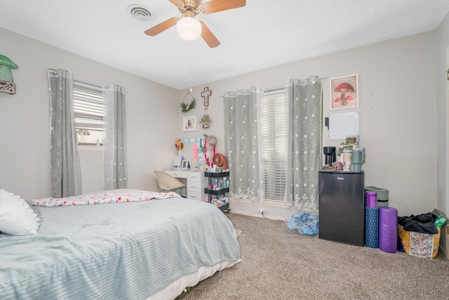 bedroom with a ceiling fan, carpet, visible vents, and refrigerator