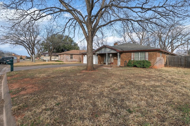 ranch-style house featuring brick siding, aphalt driveway, an attached garage, fence, and a front yard