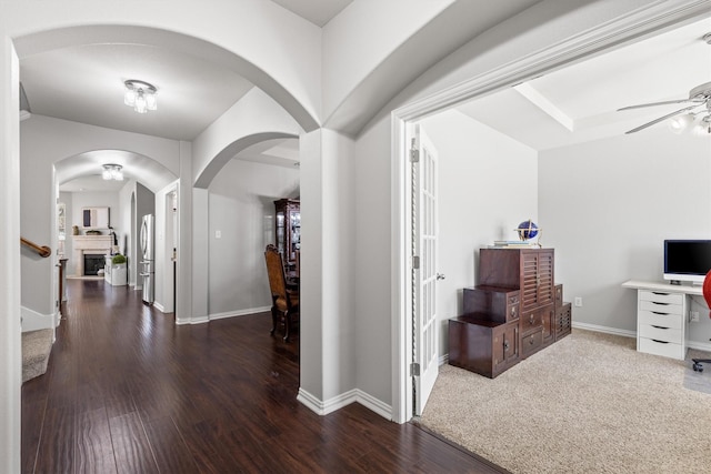 entryway featuring a fireplace, stairway, ceiling fan, wood finished floors, and baseboards