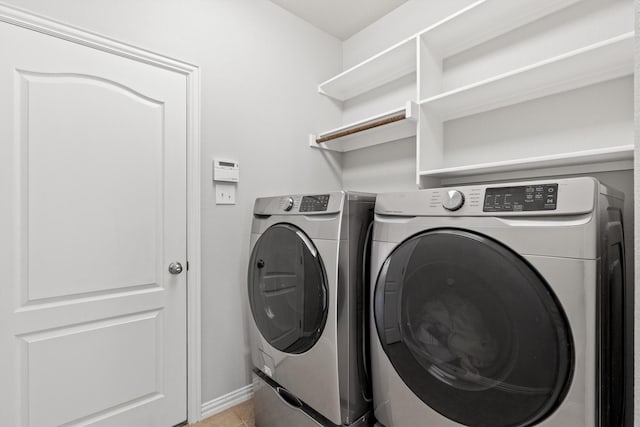 washroom featuring laundry area, baseboards, washing machine and clothes dryer, and light tile patterned floors