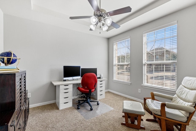 office featuring a tray ceiling, light colored carpet, ceiling fan, and baseboards