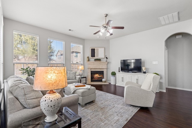 living room with arched walkways, dark wood-style floors, visible vents, and baseboards