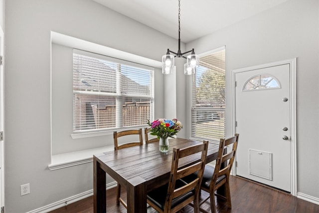 dining area with dark wood-type flooring, a chandelier, and baseboards