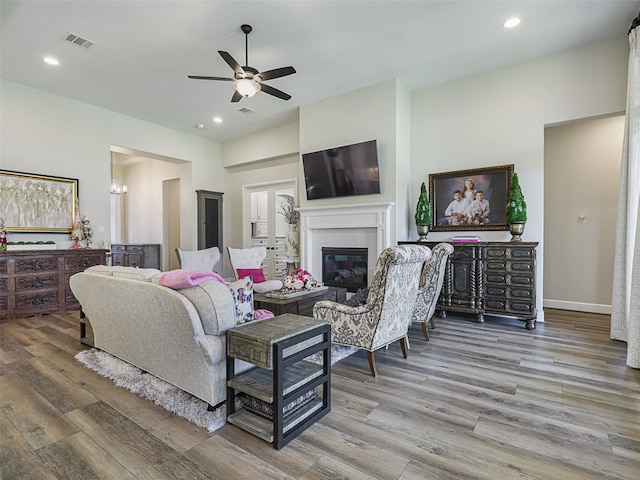 living room with recessed lighting, visible vents, a glass covered fireplace, wood finished floors, and baseboards