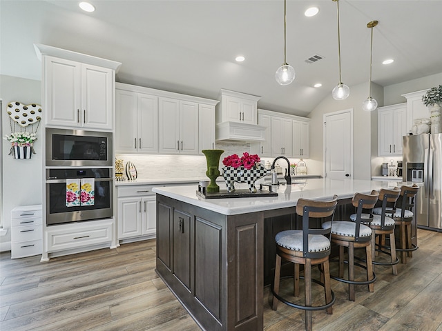 kitchen featuring light countertops, appliances with stainless steel finishes, custom exhaust hood, and white cabinetry