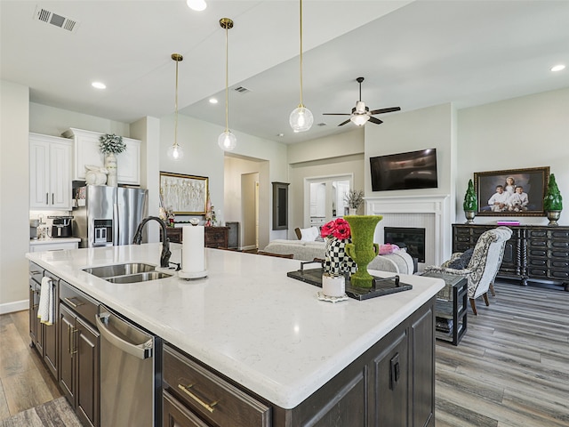 kitchen with stainless steel appliances, visible vents, white cabinetry, a sink, and wood finished floors