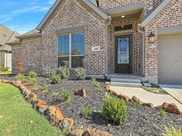 doorway to property featuring a garage and brick siding