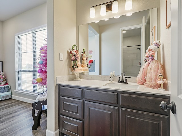 full bath with wood finished floors, vanity, and baseboards