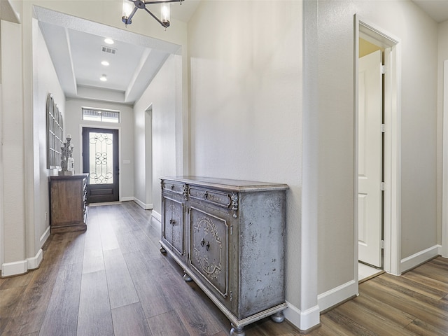 entryway featuring a tray ceiling, dark wood-type flooring, visible vents, and baseboards