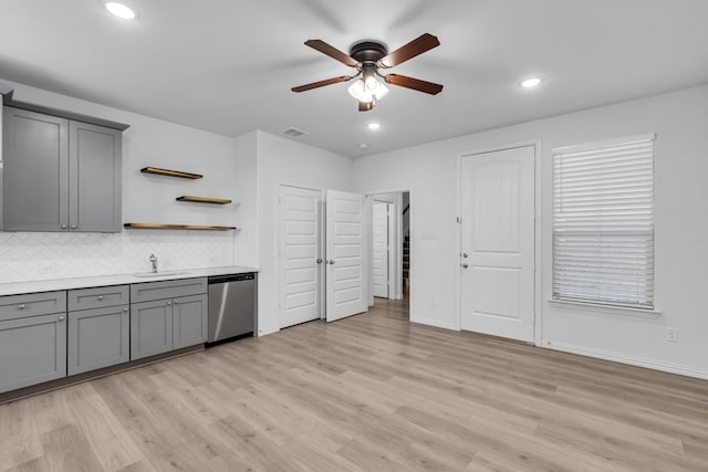 kitchen with gray cabinets, visible vents, stainless steel dishwasher, a sink, and light wood-type flooring