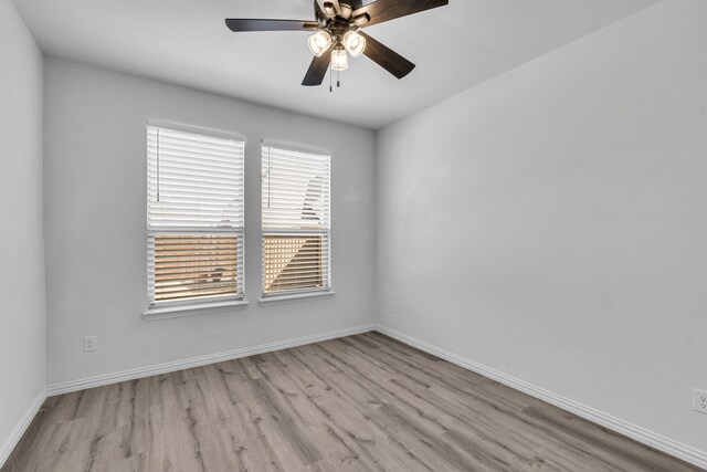 empty room with wood finished floors, a ceiling fan, and baseboards