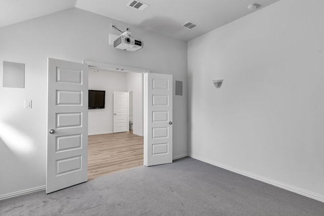 unfurnished room with carpet floors, baseboards, visible vents, and vaulted ceiling