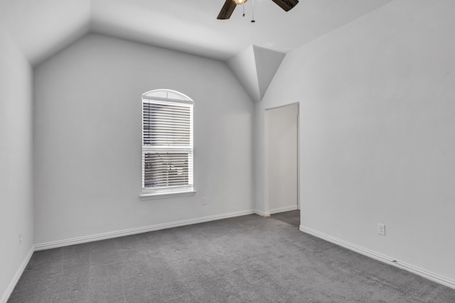 carpeted spare room with a ceiling fan, vaulted ceiling, and baseboards