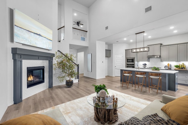 living area featuring light wood-type flooring, a tile fireplace, and visible vents