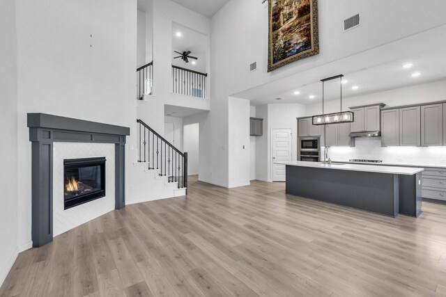 kitchen with light countertops, gray cabinetry, appliances with stainless steel finishes, light wood-style floors, and a tile fireplace