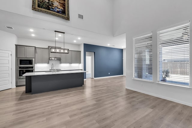 kitchen featuring oven, a sink, open floor plan, gray cabinets, and built in microwave