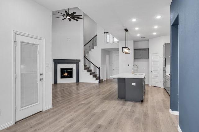 kitchen featuring open floor plan, ceiling fan, light wood-type flooring, and a glass covered fireplace