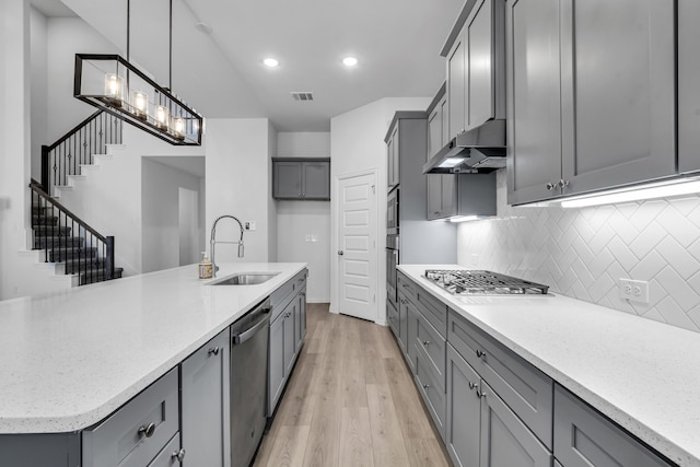 kitchen with under cabinet range hood, stainless steel appliances, a sink, visible vents, and gray cabinets