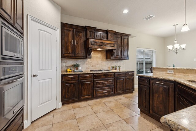 kitchen with visible vents, appliances with stainless steel finishes, light stone countertops, dark brown cabinets, and a sink