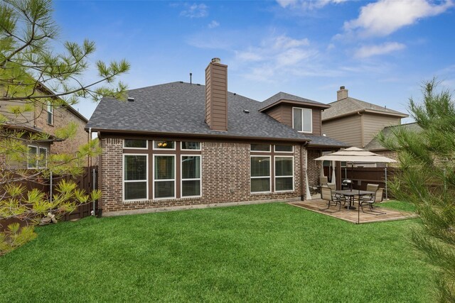 rear view of house featuring a yard, a patio, a chimney, a shingled roof, and a fenced backyard