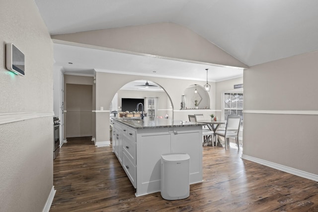 kitchen with light stone counters, white cabinetry, vaulted ceiling, an island with sink, and dark wood finished floors