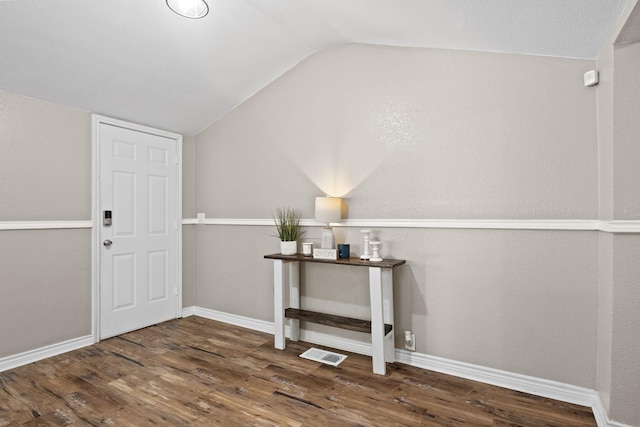 foyer with vaulted ceiling, wood finished floors, visible vents, and baseboards