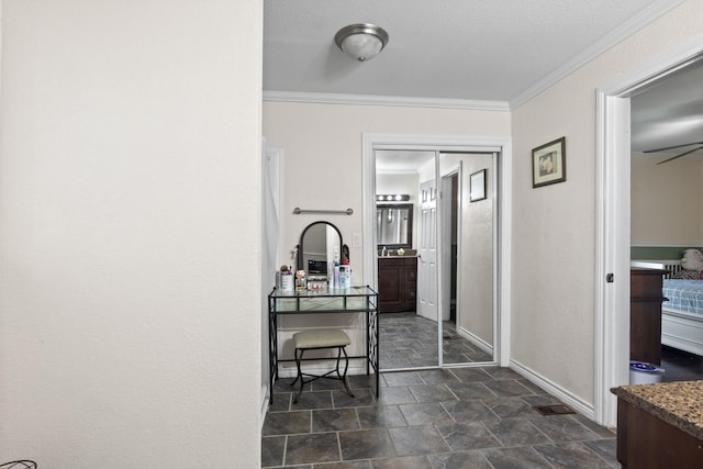 hall featuring stone finish flooring, ornamental molding, and baseboards