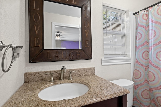 bathroom with toilet, a textured wall, curtained shower, and vanity