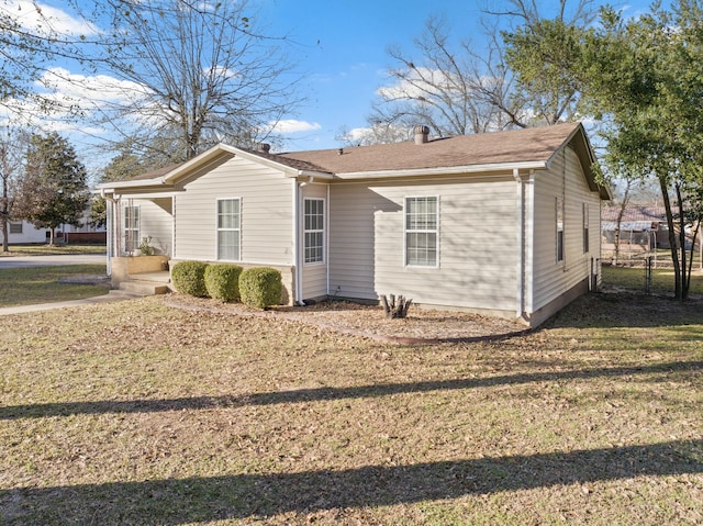 view of side of property featuring a yard, a chimney, and fence