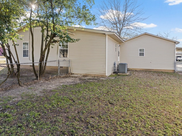 back of property with crawl space, central AC unit, a lawn, and fence