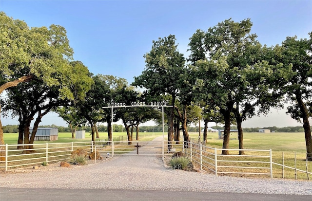 view of community featuring a gate, a rural view, fence, and a lawn