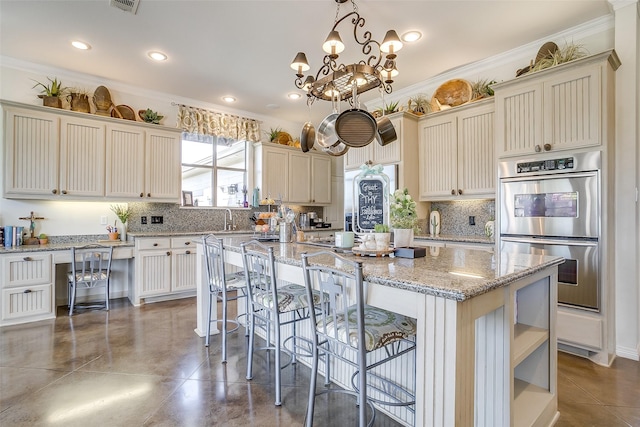 kitchen featuring a kitchen island, crown molding, stainless steel double oven, a kitchen bar, and backsplash