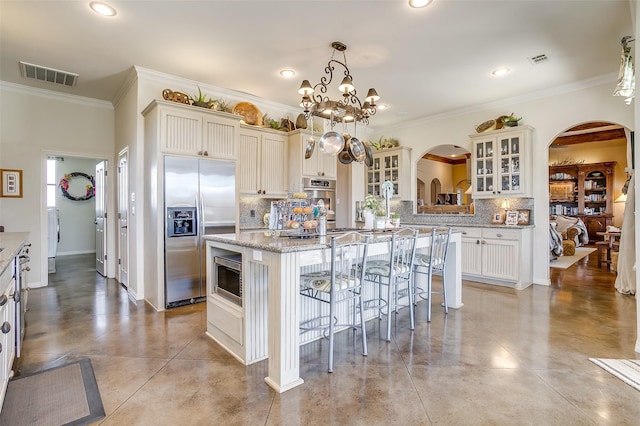 kitchen featuring built in appliances, concrete floors, a kitchen island, visible vents, and a kitchen breakfast bar