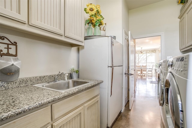 clothes washing area with cabinet space, a sink, and independent washer and dryer