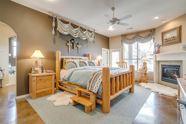 bedroom featuring a glass covered fireplace, visible vents, ceiling fan, and baseboards