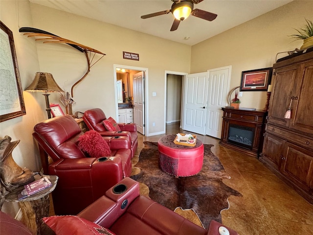 tiled living area featuring ceiling fan, a glass covered fireplace, and baseboards