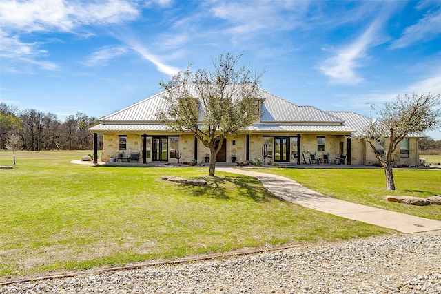 exterior space featuring stone siding, a lawn, driveway, and metal roof