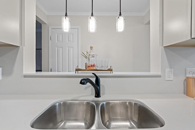 room details with ornamental molding, light countertops, a sink, and decorative light fixtures