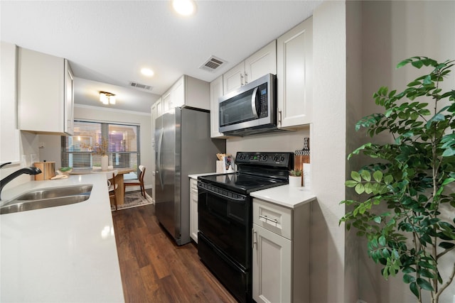 kitchen featuring stainless steel appliances, light countertops, visible vents, dark wood-type flooring, and a sink