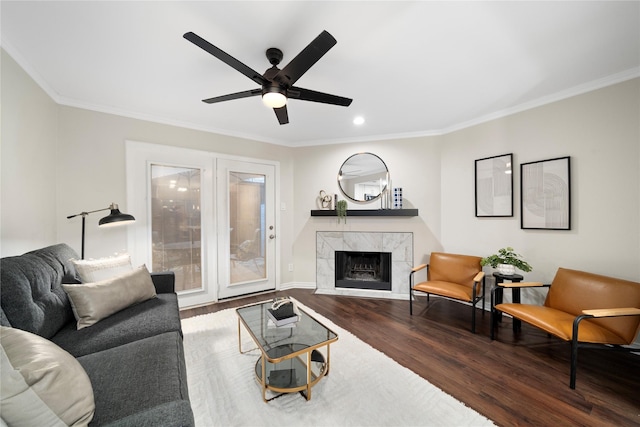 living area with ornamental molding, a fireplace, baseboards, and wood finished floors