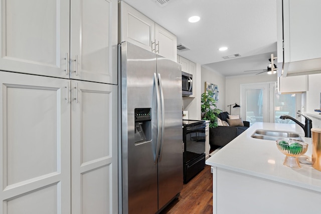 kitchen with visible vents, white cabinets, dark wood-style floors, stainless steel appliances, and a sink