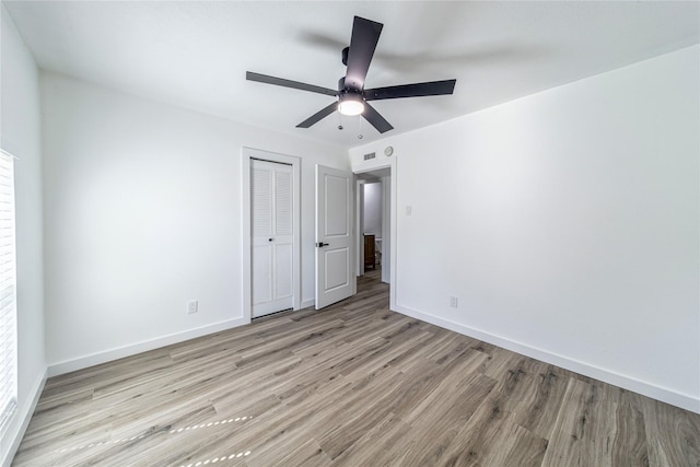 unfurnished bedroom with wood finished floors, a closet, baseboards, and ceiling fan