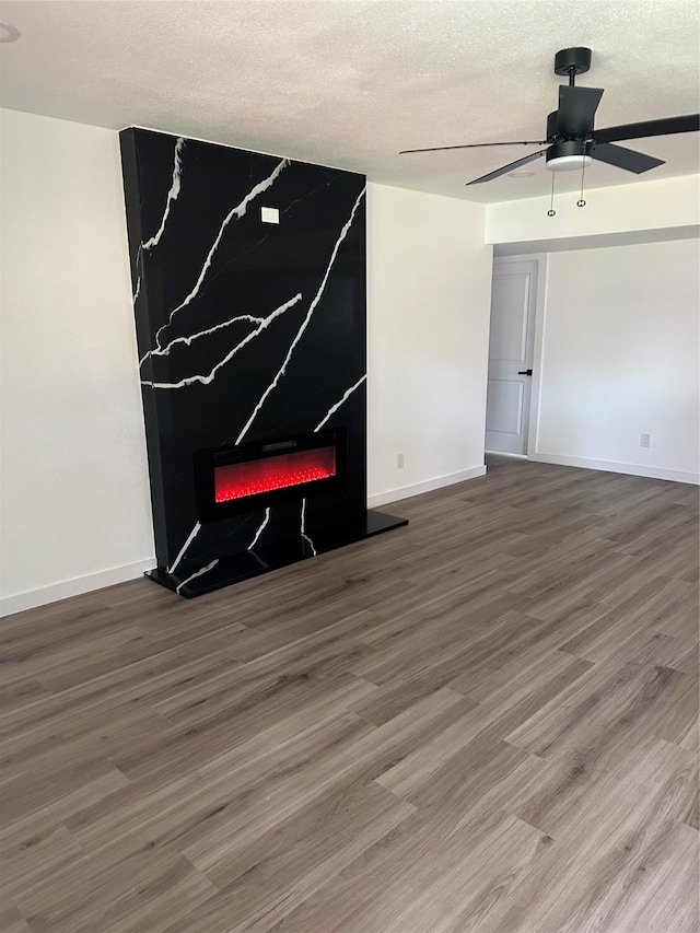 6305 Pine St, Rowlett, TX 75089 - unfurnished living room with a warm lit fireplace, ceiling fan, wood finished floors, baseboards, and a textured ceiling