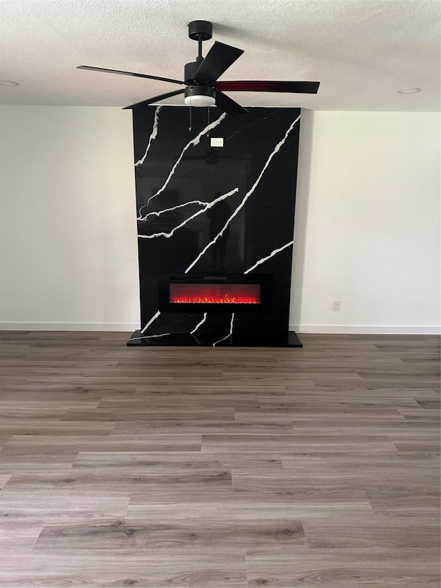 6305 Pine St, Rowlett, TX 75089 - detailed view of ceiling fan, a textured ceiling, wood finished floors, a glass covered fireplace, and baseboards