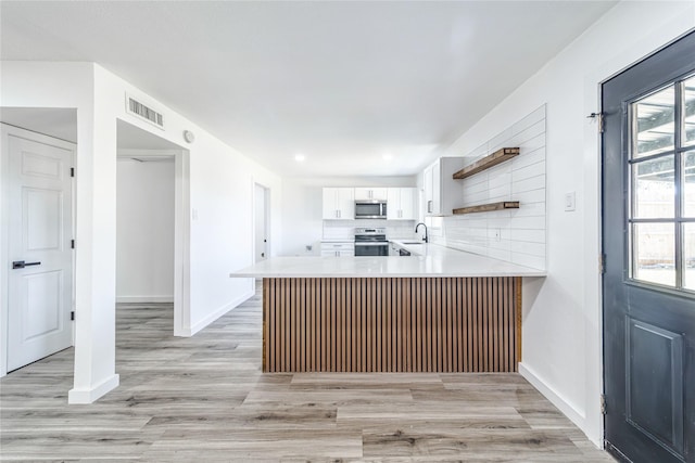 kitchen featuring stainless steel appliances, light countertops, backsplash, white cabinetry, and a sink